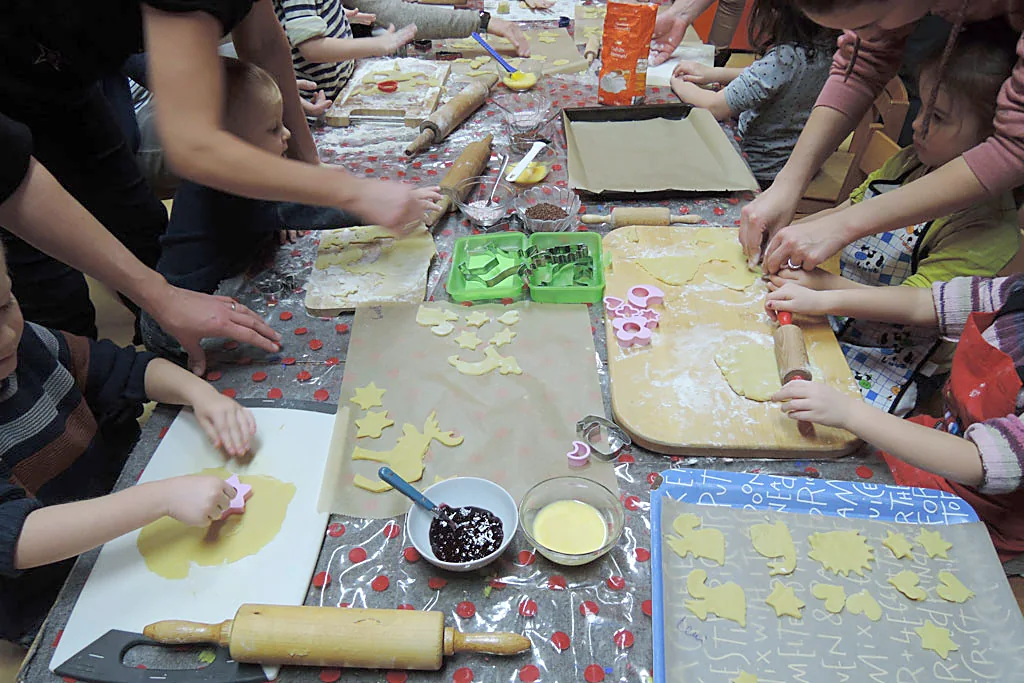 Kinder rollen Teig aus und stechen Plätzchen aus
