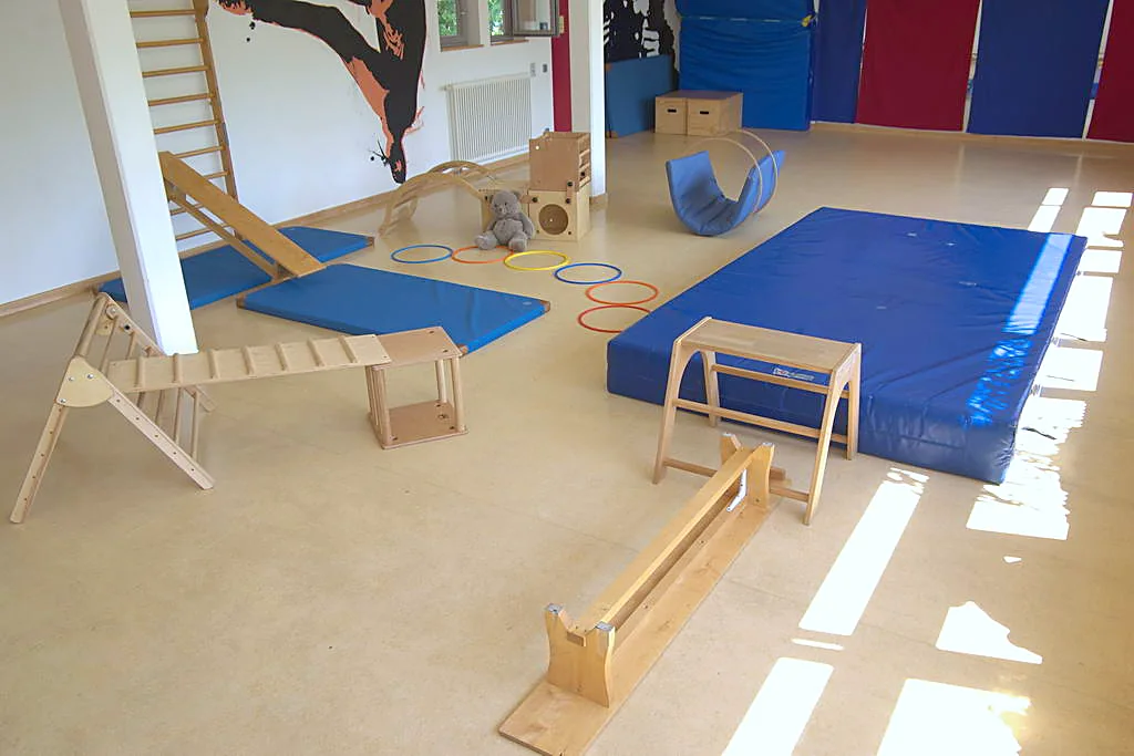 Bewegungsraum mit Matten, Kletterbrett und Balancierbalken
